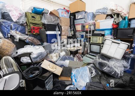 Hoarder House Schlafzimmer vollgepackt mit Kleidertaschen, Haushaltsgegenständen, alter Elektronik und anderem Müll. Stockfoto
