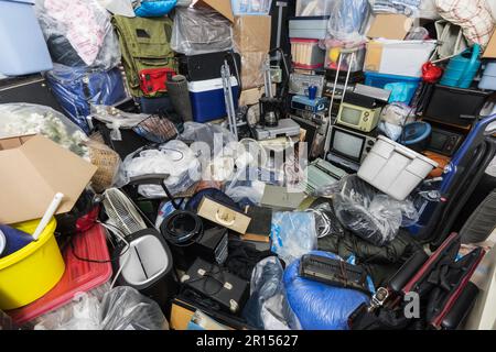 Hoarderhaus mit Kleidertaschen, Haushaltsgegenständen, alter Elektronik und anderem Müll. Stockfoto