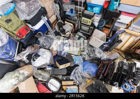 Schrotthaufen mit Kleidertaschen, Haushaltsgegenständen, alter Elektronik und verschiedenen Gegenständen. Stockfoto