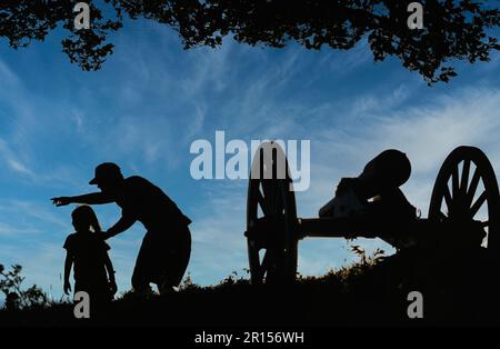 Vater weist auf einen Gegenstand von historischer Bedeutung für seine kleine Tochter in einem Bürgerkrieg Memorial Park neben einem antiken Kanon hin Stockfoto