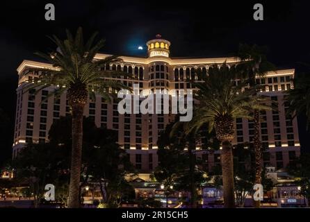 Das Bellagio Hotel and Casino in Las Vegas, Nevada, USA, mit Palmen vor der Tür während einer Mondfinsternis direkt vor dem Turm des Resorts. Stockfoto