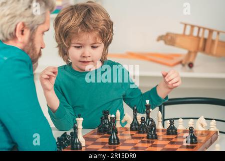 Glücklicher Vater und Sohn. Spiele und Aktivitäten für Kinder. Männerlehrer spielt Schach mit Vorschulkind. Stockfoto