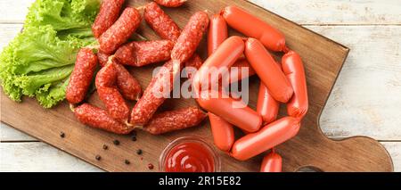 Köstliche Würstchen mit Sauce und Salat auf Holzbrett Stockfoto
