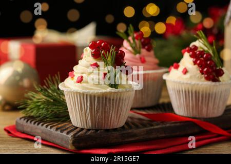 Köstliche Cupcakes und Weihnachtsdekorationen auf einem Holztisch Stockfoto