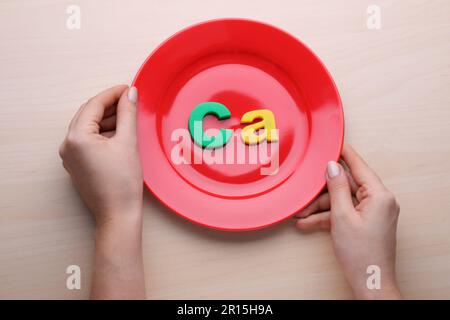 Halteplatte mit Papiersymbol Ca (Calcium) am Holztisch, Draufsicht Stockfoto