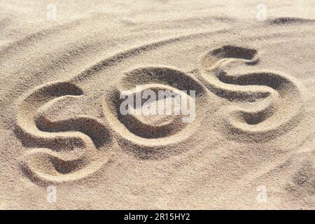 SOS-Nachricht wurde am Sandstrand draußen geschrieben Stockfoto