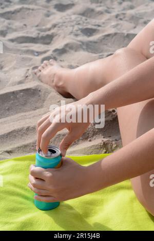 Frau öffnet Aluminiumdose mit Getränk auf gelber Decke, Nahaufnahme Stockfoto