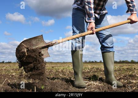 Mann gräbt Erde mit Schaufel auf dem Feld, Nahaufnahme Stockfoto