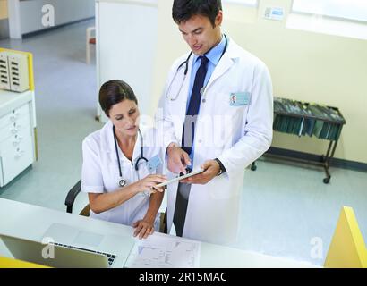 Korrelation der medizinischen Daten. Ein medizinisches Team, das eine Patientenakte durchsucht. Stockfoto