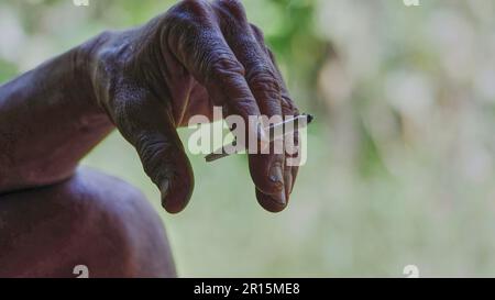 Eine Hand, die eine Zigarette zwischen Zeige- und Mittelfinger hält Stockfoto