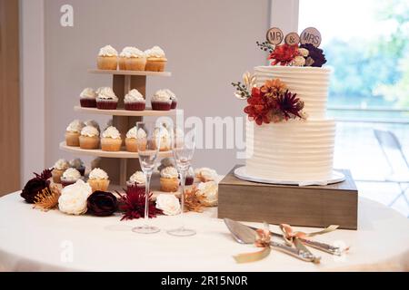 Hochzeitstorte und Hochzeitsturm mit rotem Samt und Vanille, Orange, Braun, Gold und burgunderroten Blumen Stockfoto