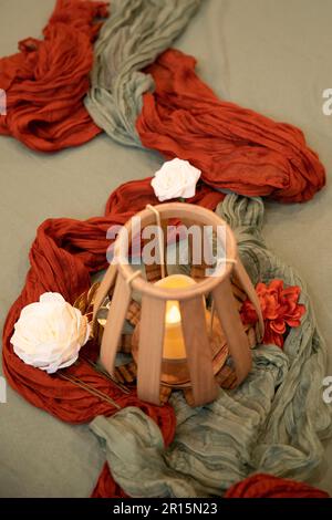 Nahaufnahme der Hochzeitsdekoration mit Holzlaternen, mit Schwerpunkt auf dekorativen Stoffen und Seidenblumen, künstliche Blumen Stockfoto