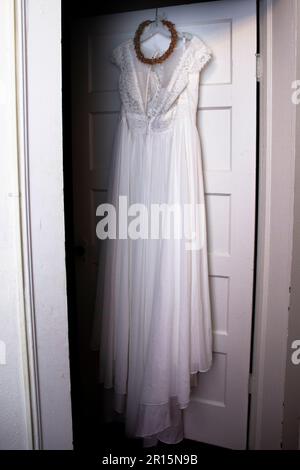 boho Weißes Hochzeitskleid Korsett aus der Nähe mit orangefarbenem Kopfkranz, Blumenkrone, geblümtem Kopfstück, das in der Tür liegt Stockfoto