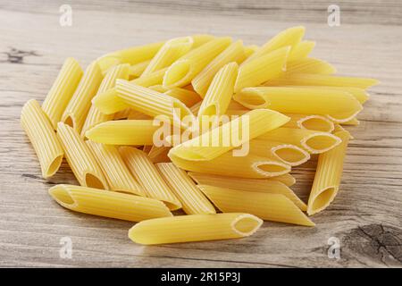 Rohe Penne-Rigate-Nudeln isoliert auf grauem Holzhintergrund Stockfoto