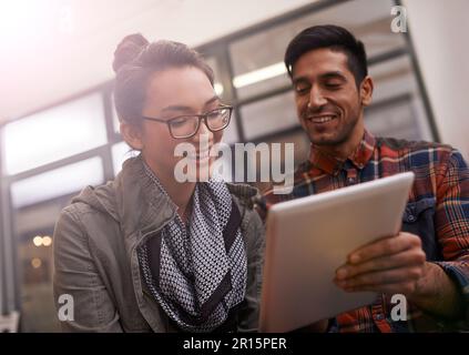 Schau, Baby, kostenloses WLAN. Ein junges Paar, das zusammen ein digitales Tablet benutzt. Stockfoto