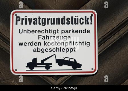 Schild mit deutscher Inschrift Privatgrundstück, parkende Autos werden abgeschleppt. Übersetzung: Privateigentum, geparkte Autos werden abgeschleppt Stockfoto