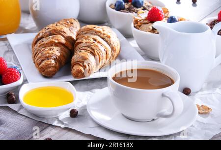 Frühstück mit Kaffee, Orangensaft, Croissants, Ei, Müsli und Obst. Ausgewogene Ernährung Stockfoto