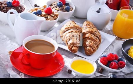 Frühstück mit Kaffee, Orangensaft, Croissants, Ei, Müsli und Obst. Ausgewogene Ernährung Stockfoto