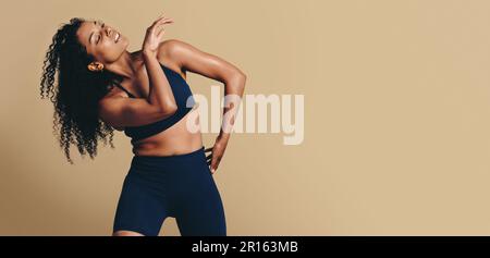 Fit Woman in Sportbekleidung tanzt anmutig im Studio und zeigt ihre sportliche Stärke und Form. Sie inspiriert andere dazu, ihre eigene Athletik anzunehmen Stockfoto