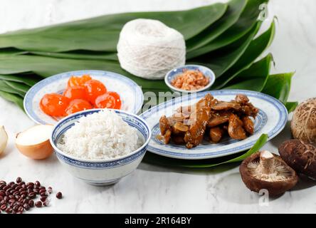 Zutaten für Zongzi, chinesischer Reis, Teigtaschen, Bakcang für Drachenbootfestival. Bambusblatt, Gesalzenes Ei, Huhn, Knoblauch, Zwiebeln, Und Ric Stockfoto