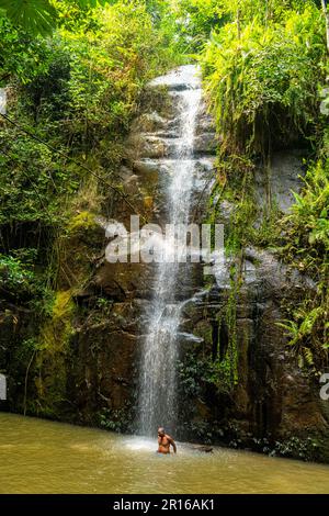 Ein Mann, der ein Bad unter einem kleinen Wasserfall in der Nähe des Zongo-Wasserfalls, DR Kongo, nimmt Stockfoto