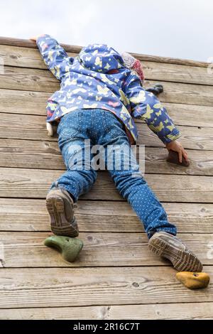 Mädchen (5) klettert auf eine Kletterwand, Kiel, Deutschland Stockfoto