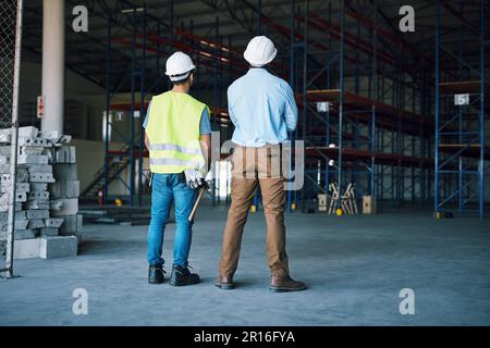 Eine Übereinstimmung, die in der Technik hergestellt wurde. Zwei Bauarbeiter inspizieren eine Baustelle. Stockfoto