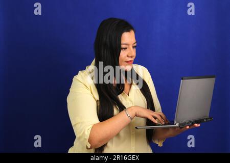 Eine dunkelhaarige lateinische Erwachsene Frau verwendet Laptop für die Arbeit, Online-Shopping, Dating in Apps sieht aufgeregt aus und zeigt mit dem Finger Stockfoto