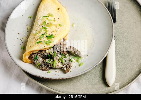 Omelette mit Morchelpilzen und Käse in einer cremigen Sauce mit Kräutern, Nahaufnahme. Stockfoto