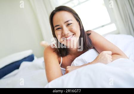 Wach auf und schlafe. Eine attraktive junge Frau, die morgens auf ihrem Bett liegt. Stockfoto