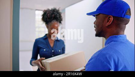 Glückliche junge Frau akzeptieren Karton ab Lieferung Mann Stockfoto