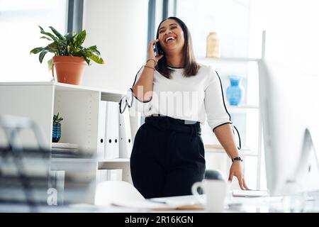 Sie hat am Telefon eine freundliche und professionelle Art zu telefonieren. Eine junge Geschäftsfrau, die mit einem Handy in einem Büro spricht. Stockfoto