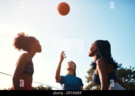 Möge das beste Team gewinnen. Eine vielfältige Gruppe von Sportlerinnen, die tagsüber gemeinsam ein Wettkampfspiel mit Basketball spielen. Stockfoto