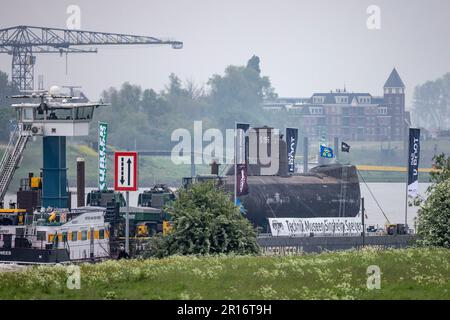 Bimmen, Deutschland. 12. Mai 2023. Das U-Boot auf einem schwimmenden Ponton passiert das Dorf Bimmen am Rhein. U 17, ein U-Boot der Klasse 206A, soll im Speyer Museum of Technology ankommen. Das Boot, das mehr als 35 Jahre lang der deutschen Marine diente, verließ Kiel am 28. April auf einem schwimmenden Ponton über den Kieler Kanal, die Nordsee und den Rhein in Richtung Speyer. Kredit: Christoph Reichwein/dpa/Alamy Live News Stockfoto