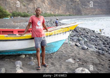 Mann in der Nähe eines traditionellen hölzernen Fischerboots an einem Strand in einem kleinen Fischerdorf von tarrafal de monte trigo auf der insel santo antao, cabo verde Stockfoto