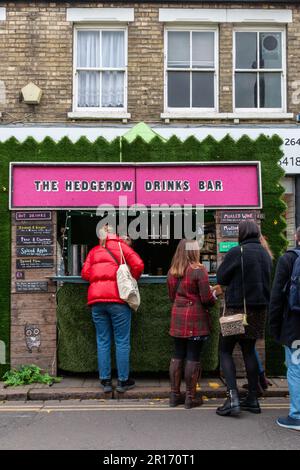 In der Popup-Bar Hedgerow Drinks auf der Mill Road Winter Fair in Cambridge, Großbritannien, warten viele Leute darauf, Getränke zu bestellen Stockfoto