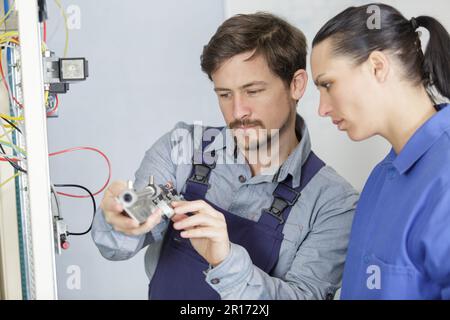 Vorgesetzter erklärt der Arbeiterin den elektronischen Bestandteil Stockfoto