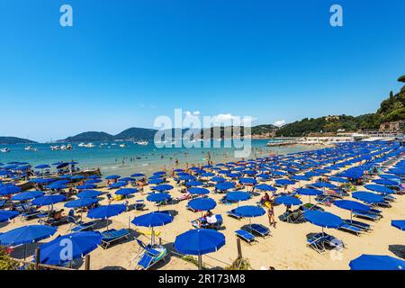 Strand von Lerici mit blauen Sonnenschirmen, Touristenresort im Golf von La Spezia, Ligurien, Italien, Europa. Kleines Dorf San Terenzo und Porto Venere. Stockfoto