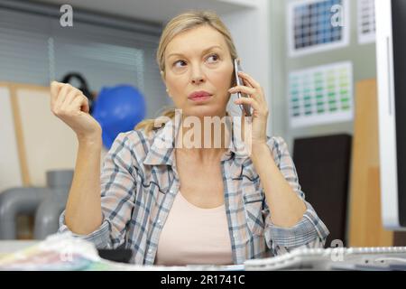 Reife Frau, die einen Anruf vom Heimbüro entgegennimmt Stockfoto