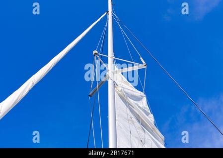 Segel setzen auf einer Yacht. Junger Mann Captan hebt das Segel einer Katamaranjacht während der Fahrt Stockfoto