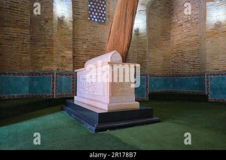 Weißes Marmorgrab mit großem Holzzweig. Im Sheikh Hovendi at-Tahur Mausoleum in Taschkent, Usbekistan. Stockfoto