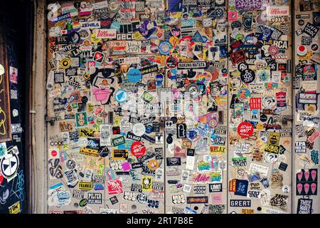 Mehrere Aufkleber, die eine Wand bedecken und so einen Montagestil erzeugen. Gelegen in einer japanischen Seitenstraße in Tokio, Japan Stockfoto
