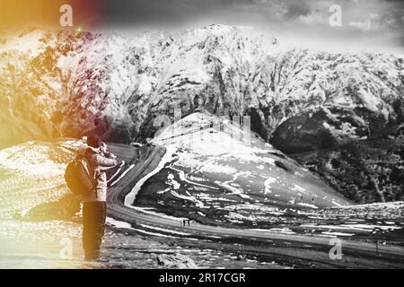 Stepantsminda, Gergeti, Georgia. Sunlit Man Tourist Traveler Fotograf Fotografiert Bilder Der Atemberaubenden Georgianischen Berglandschaft In Den Frühen Jahren Stockfoto