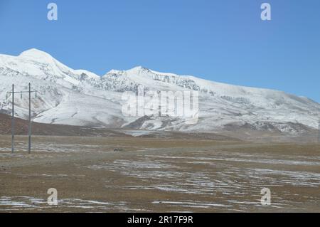 Volksrepublik China, Tibet: Die Schneelinie auf dem Hochplatau mit schneebedeckten Bergen als Kulisse. Stockfoto