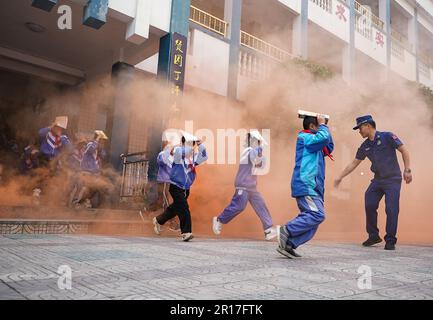 QIANDONGNAN, CHINA - 12. MAI 2023 - Grundschulschüler nehmen an einer Evakuierungsübung unter dem Kommando der Feuerwehrleute in Qiandongnan Miao an Teil Stockfoto