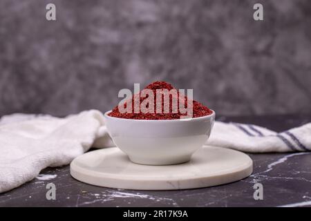 Sumac auf dunklem Hintergrund. Getrocknete gemahlene rote Sumac-Gewürze in einer Holzschüssel Stockfoto