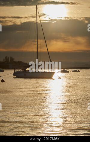 Eine Silhouette einer festgemachten Yacht an der Mündung des Teign, im Hafen von Teignmouth, Devon, Großbritannien. Stockfoto