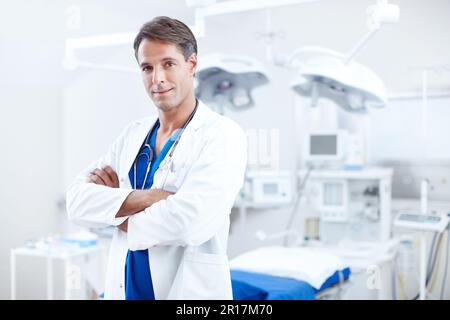 Der perfekte Arzt. Ein selbstbewusster Arzt, der im OP mit gekreuzten Armen steht. Stockfoto