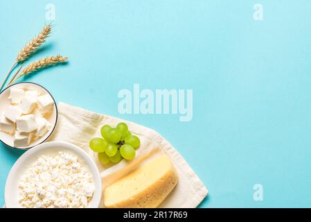 Happy Shavuot - religiöses jüdisches Urlaubskonzept mit Milchprodukten, Käseobst, Weizen auf blauem Hintergrund, Kopierbereich. Stockfoto