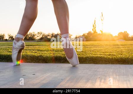 Füße einer Balletttänzerin in pointe-Schuhen bei Sonnenuntergang mit Regenbogen Stockfoto